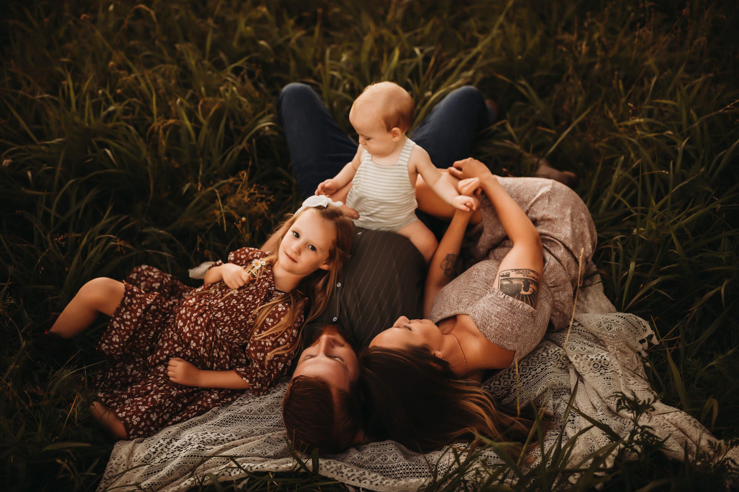 a family laying down in a field connecting and soaking in the moment.